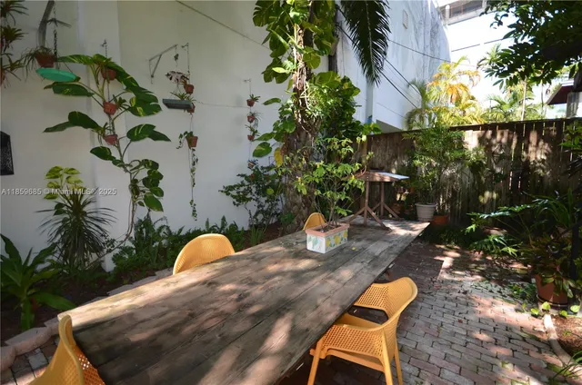 a backyard of a house with table and chairs potted plants