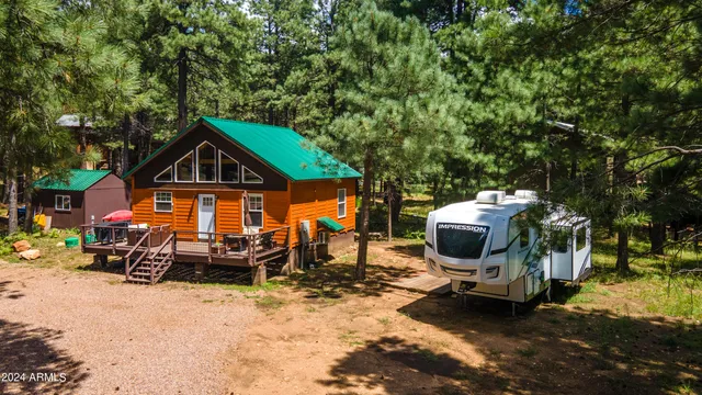 a front view of a house with wooden deck and trees