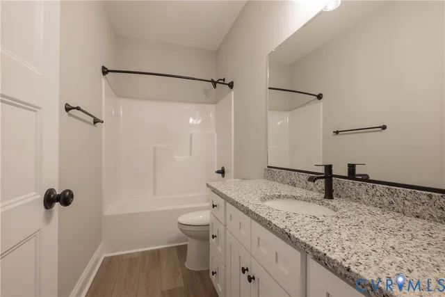 a bathroom with a granite countertop sink a toilet and a mirror