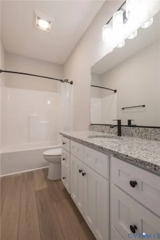 a bathroom with a granite countertop sink mirror vanity and toilet