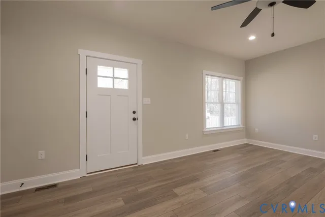 an empty room with wooden floor cabinet and windows