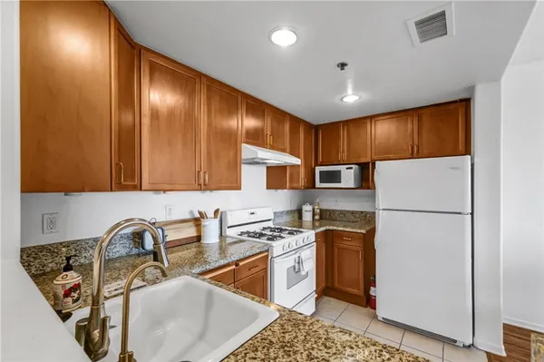 a kitchen with stainless steel appliances granite countertop a sink refrigerator and cabinets
