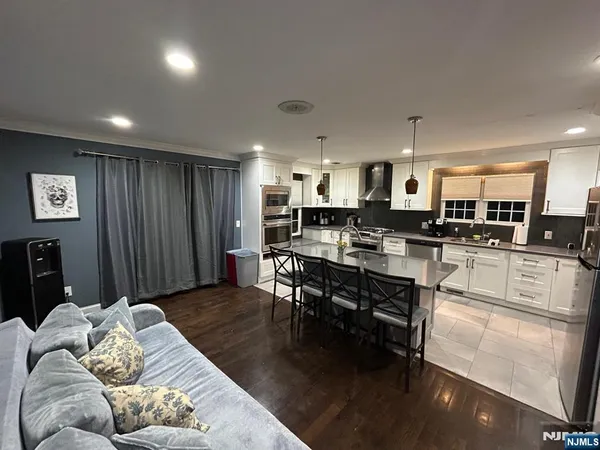 a living room with stainless steel appliances lots of furniture and kitchen view