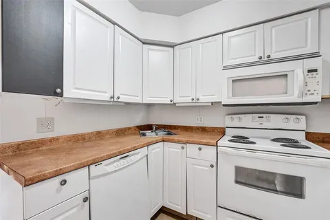 a kitchen with white cabinets and white appliances