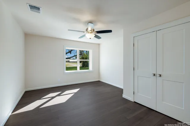 an empty room with wooden floor and a ceiling fan