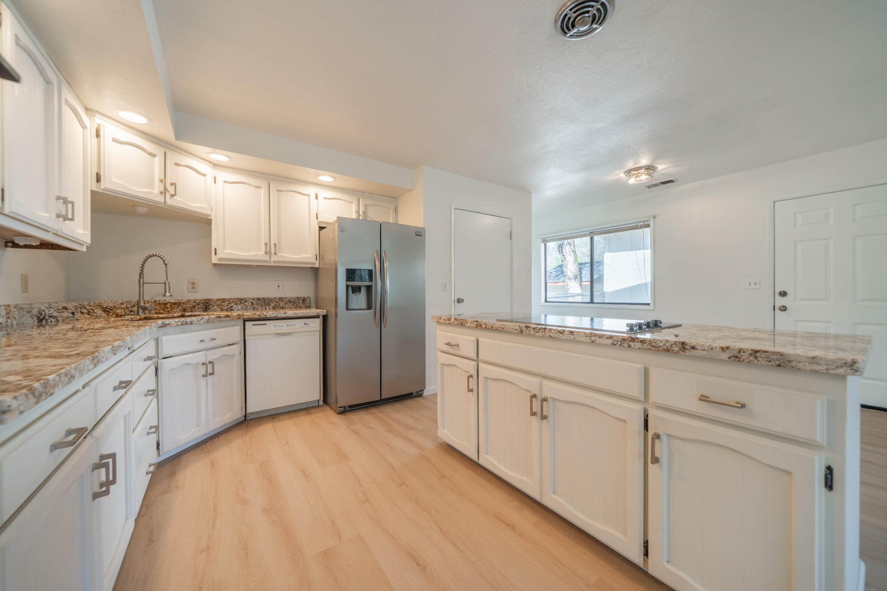 2580 Keswick Dam Road Redding, CA 96003 - Photo 14 of 60 a large kitchen with a stove a sink dishwasher a refrigerator and white cabinets with wooden floor