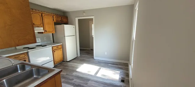 a kitchen with stainless steel appliances granite countertop a refrigerator a stove and a sink with wooden floor