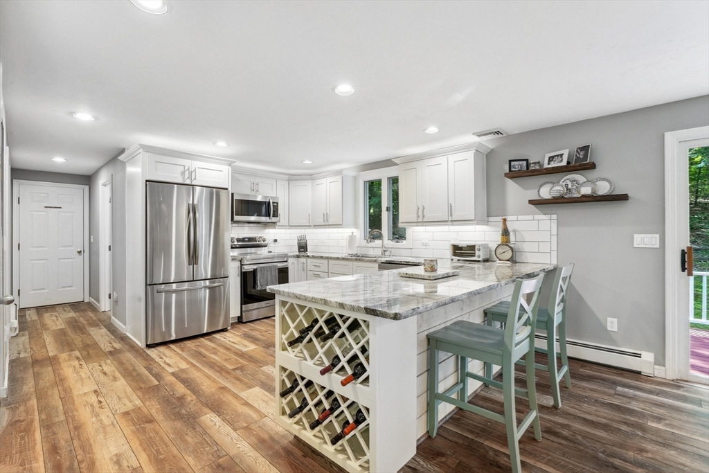 66 Dodge Road Sutton, MA 01590 - Photo 10 of 38 a kitchen with stainless steel appliances a refrigerator a sink dishwasher a stove and white cabinets with wooden floor