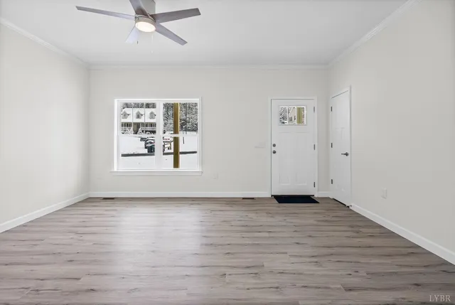 an empty room with wooden floor chandelier fan and windows