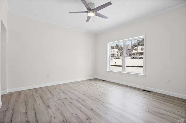 an empty room with wooden floor ceiling fan and windows