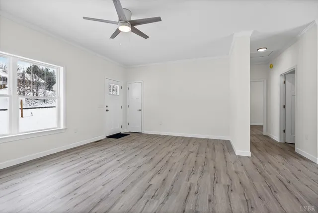 an empty room with wooden floor ceiling fan and windows