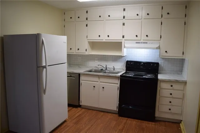a kitchen with cabinets appliances and wooden floor
