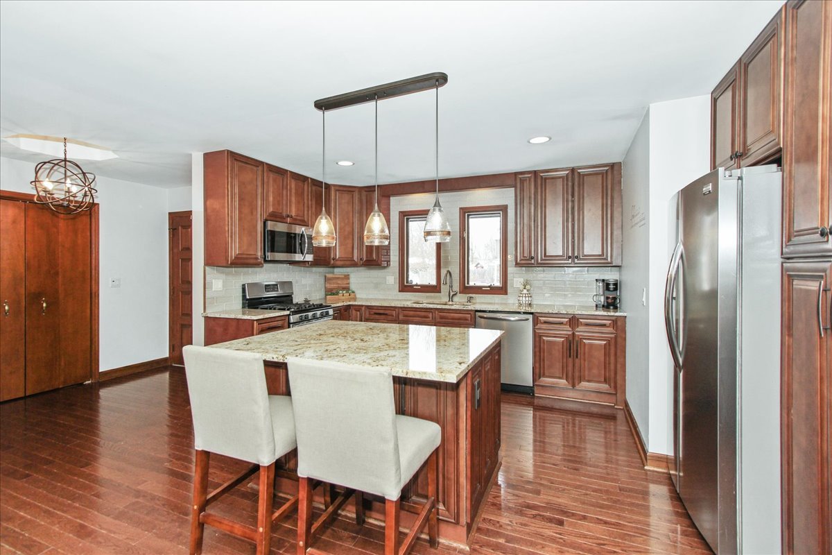 1865 Kevin Avenue Elgin, IL 60123 - Photo 16 of 48 a kitchen with stainless steel appliances granite countertop a refrigerator a stove top oven a sink dishwasher a dining table and chairs with wooden floor