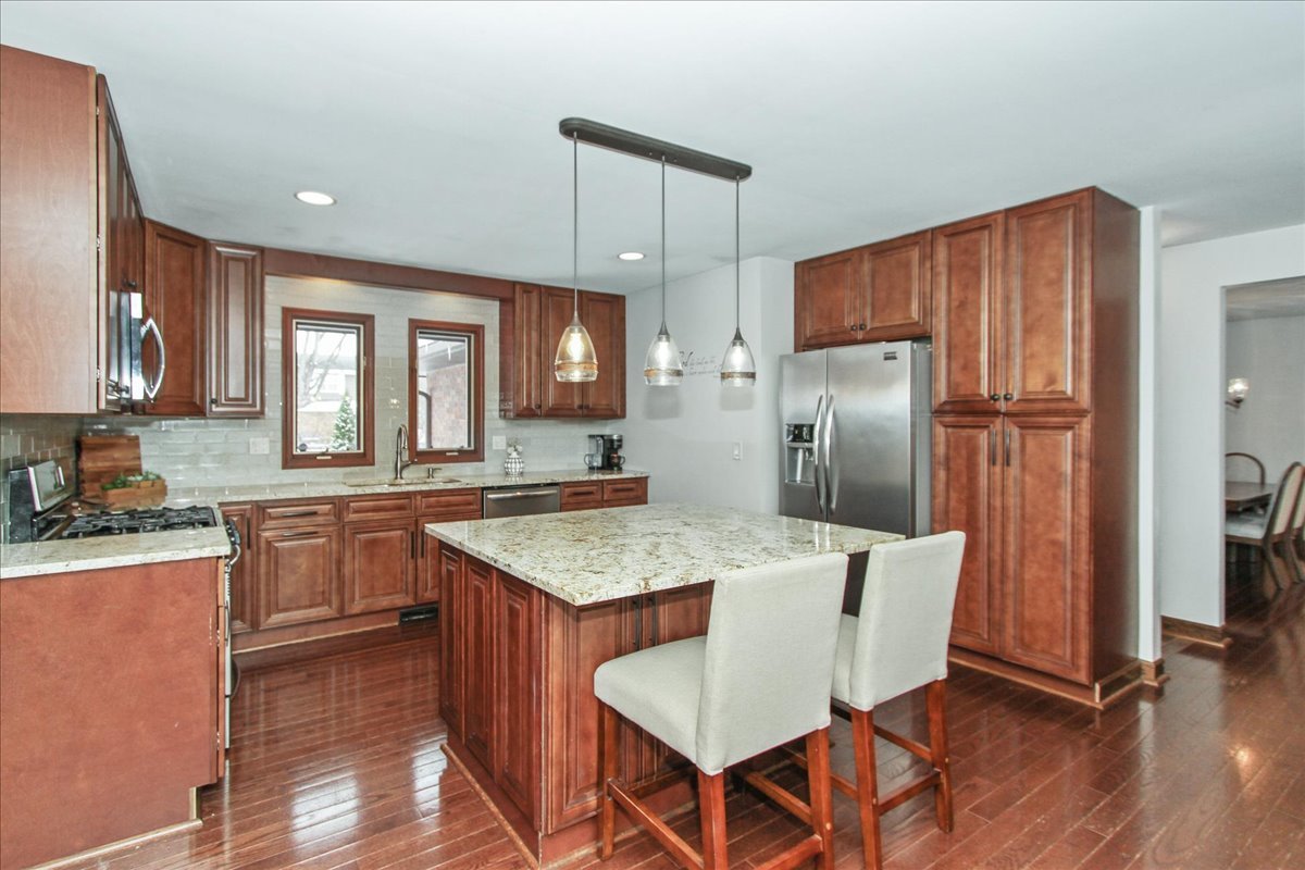 1865 Kevin Avenue Elgin, IL 60123 - Photo 19 of 48 a kitchen with stainless steel appliances granite countertop a refrigerator a sink a stove a dining table and chairs
