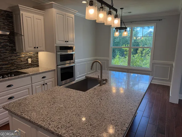a kitchen with kitchen island granite countertop a sink a counter space appliances and cabinets