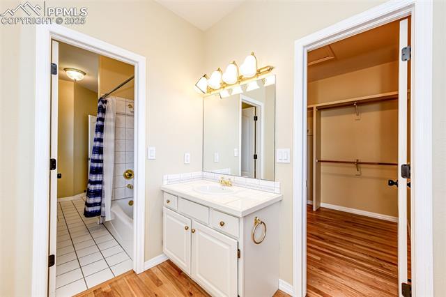 19340 Furrow Road Monument, CO 80132 - Photo 36 of 50 Full bathroom with vanity, wood finished floors, a spacious closet, baseboards, and shower / bath combination with curtain