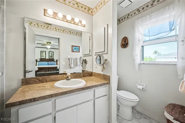 a bathroom with a granite countertop sink toilet and mirror