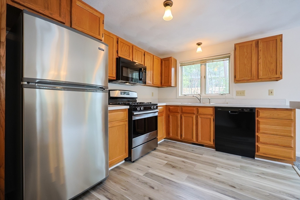 22 Deer Path, Unit 6 Maynard, MA 01754 - Photo 16 of 34 a kitchen with stainless steel appliances granite countertop a refrigerator a sink dishwasher a stove with wooden floor