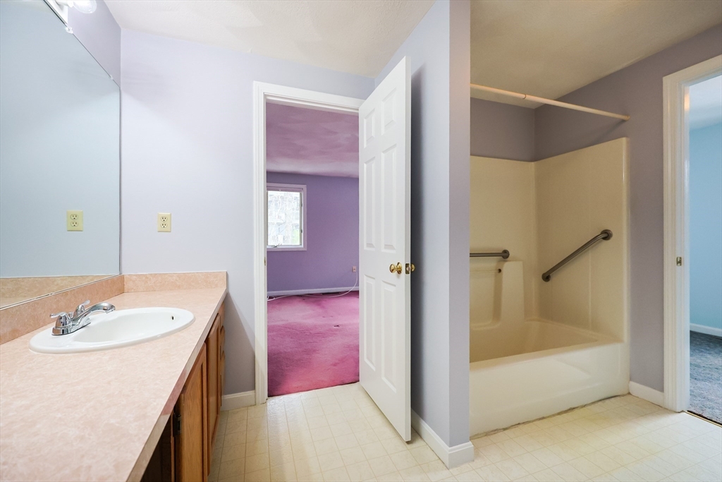 22 Deer Path, Unit 6 Maynard, MA 01754 - Photo 23 of 34 a en suite bathroom with a granite countertop sink a mirror and a bathtub