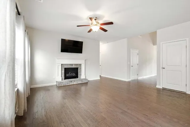 a view of an empty room with wooden floor fireplace and a window