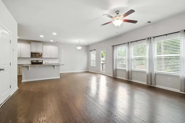 a view of an empty room with a kitchen and wooden floor
