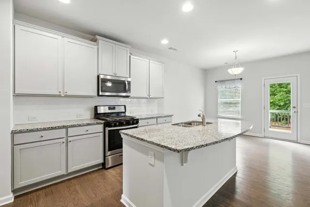 a kitchen with granite countertop white cabinets and a stove top oven