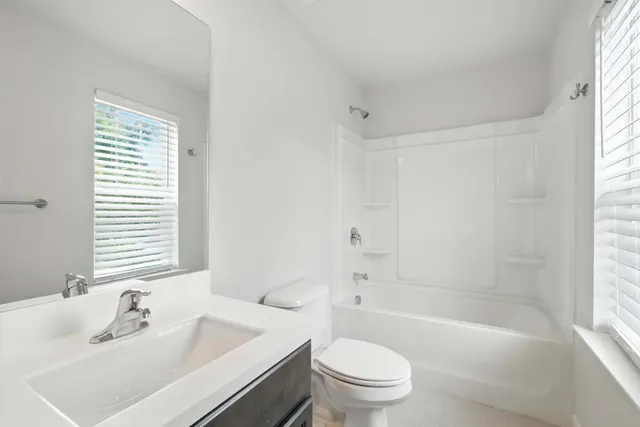 a bathroom with a bathtub shower sink vanity mirror and toilet
