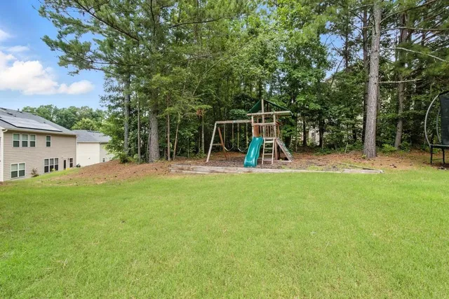 a view of a backyard with a slide trees and wooden fence