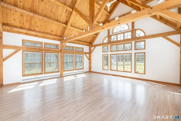 a view of an empty room with wooden floor and windows