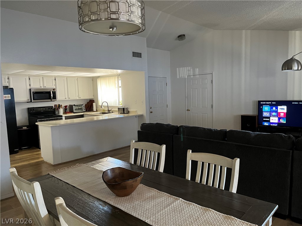6412 West Pearcrest Road Las Vegas, NV 89108 - Photo 6 of 17 An inviting open-concept layout unites the kitchen and living areas, highlighted by soaring vaulted ceilings.
