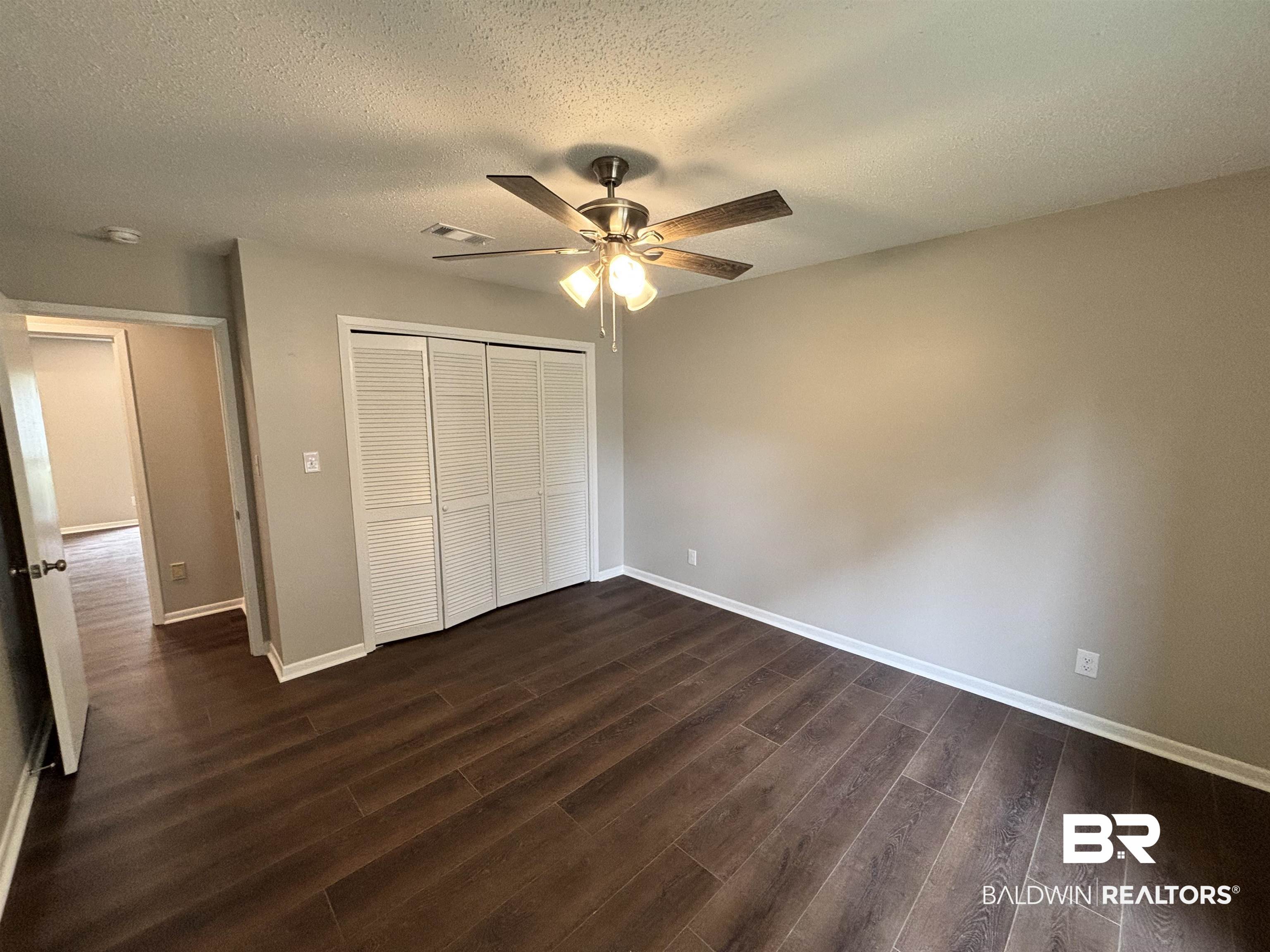 10 Soldiers Route Daphne, AL 36527 - Photo 21 of 26 Unfurnished bedroom featuring a textured ceiling, dark wood finished floors, a closet, and a ceiling fan