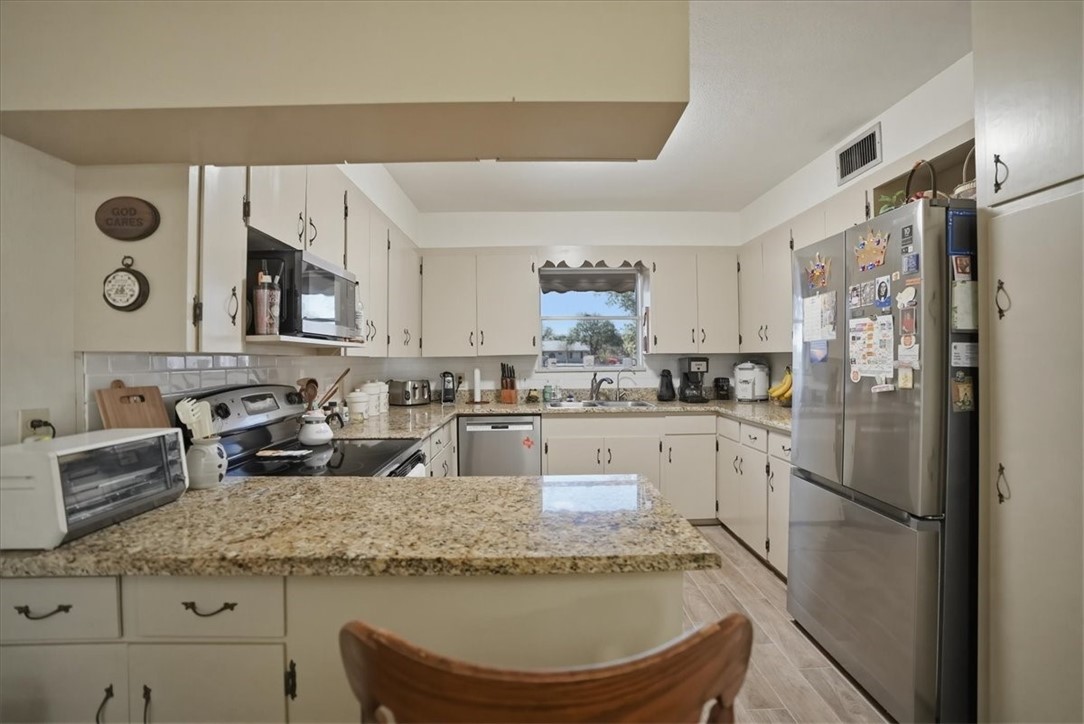 1309 Burleson Street George West, TX 78022 - Photo 8 of 32 a kitchen with stainless steel appliances granite countertop a sink refrigerator and cabinets