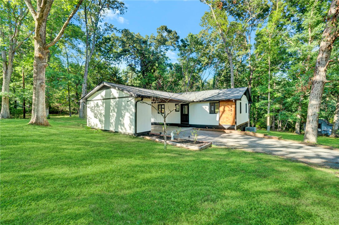A private wooded setting surrounds this charming residence, boasting ample green space and a paved driveway.