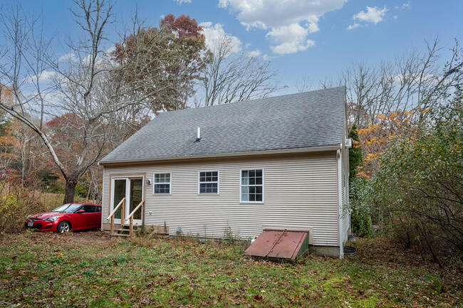 82 Deerfield Road Mashpee, MA 02649 - Photo 2 of 16 a backyard of a house with potted plants and large tree