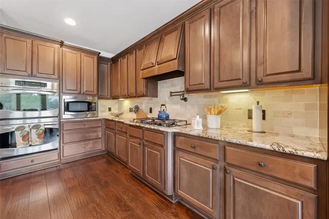 a kitchen with granite countertop wooden cabinets stainless steel appliances and wooden floor