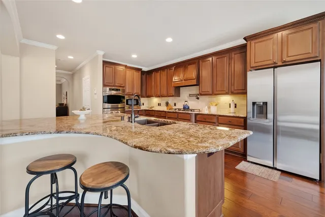 a kitchen with stainless steel appliances granite countertop a sink refrigerator and cabinets