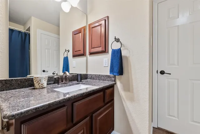 a bathroom with a granite countertop sink and a mirror