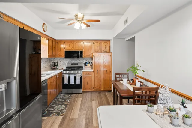 a kitchen with stainless steel appliances a stove a refrigerator a sink dishwasher with a dining table and chairs with wooden floor