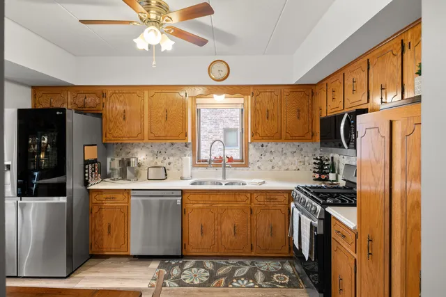 a kitchen with stainless steel appliances granite countertop a refrigerator a sink dishwasher a stove with wooden cabinets and floor