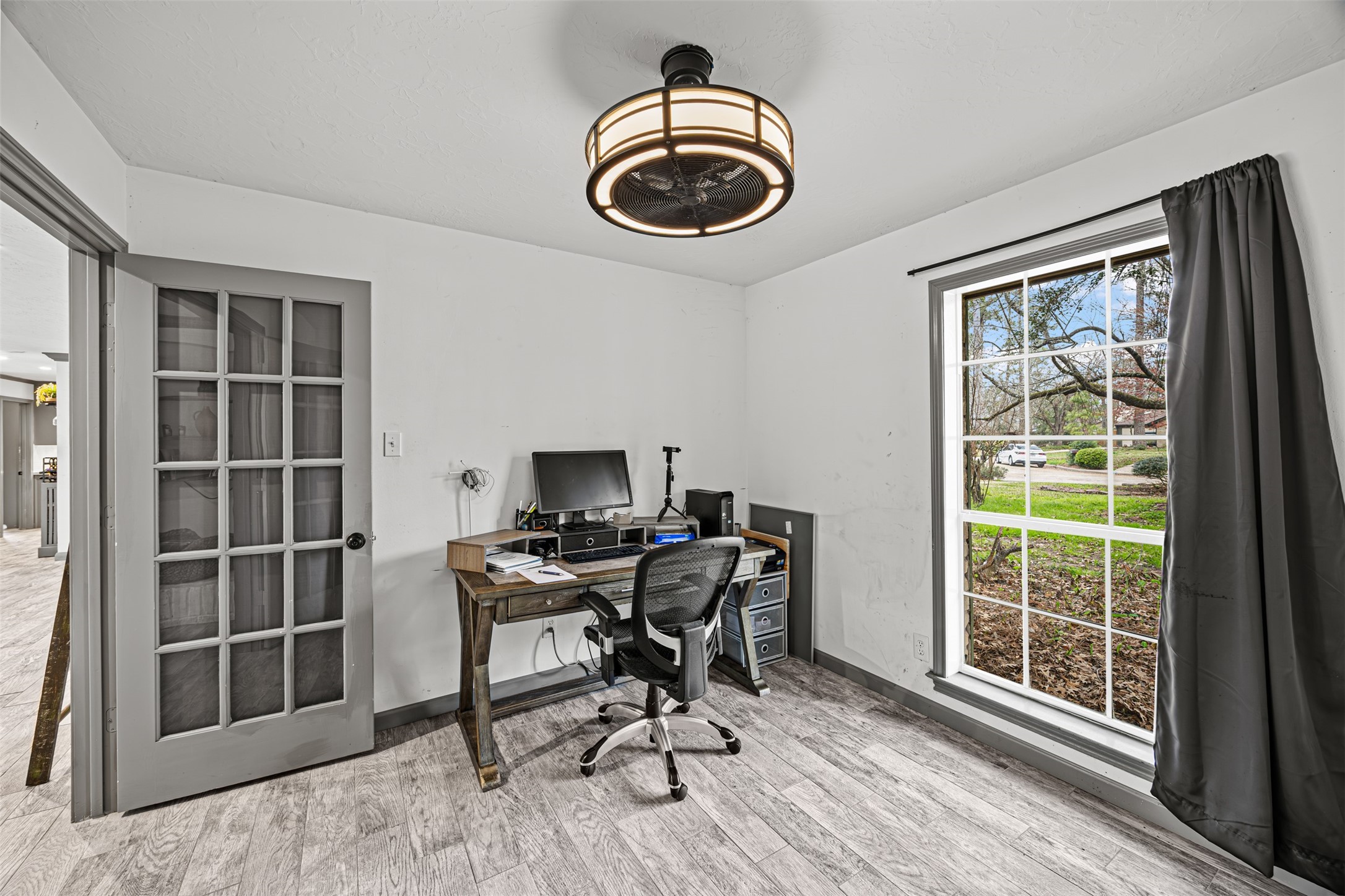 6511 Elmgrove Road Spring, TX 77389 - Photo 12 of 33 Bright home office with modern lighting and a large window offering natural light and garden views. The room includes a stylish desk setup and glass panel door. Home office can be easily converted into a playroom or media lounge.