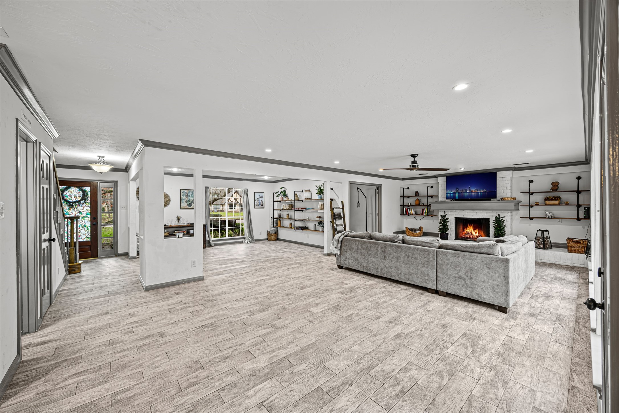 6511 Elmgrove Road Spring, TX 77389 - Photo 13 of 33 This spacious living area features modern tile flooring, a cozy fireplace, and a large sectional sofa. The room is well-lit with recessed lighting and natural light from large windows. Stylish built-in shelves provide ample storage and display space.