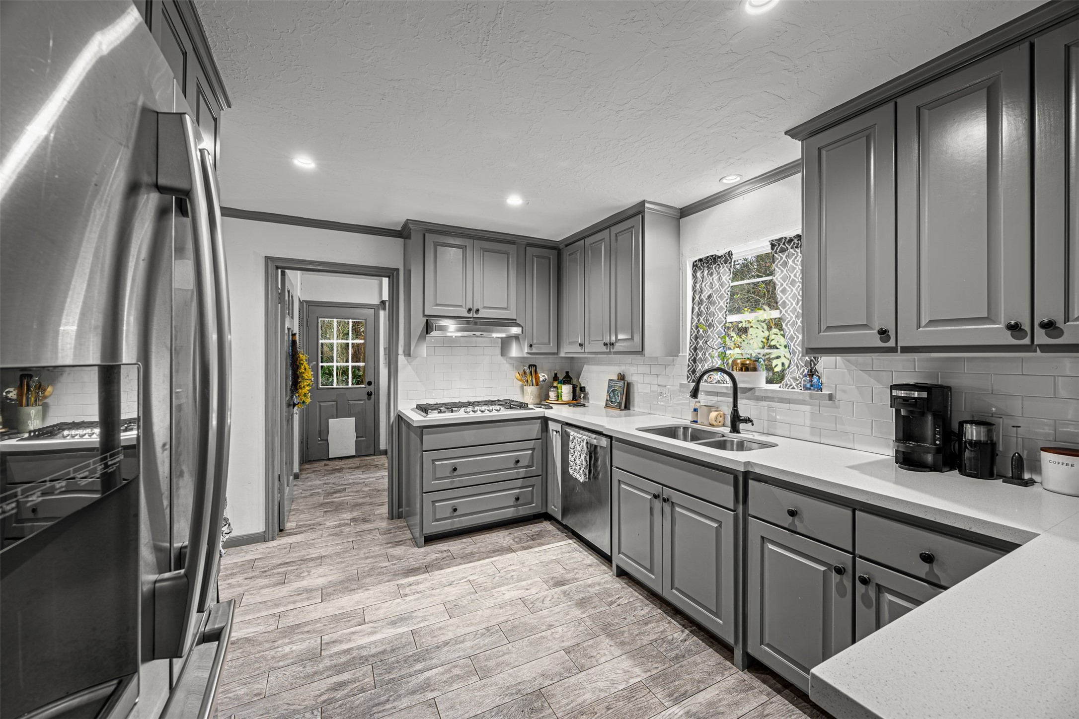 6511 Elmgrove Road Spring, TX 77389 - Photo 14 of 33 This kitchen features sleek gray cabinetry, modern stainless steel appliances, and a stylish tile floor. It has ample counter space and a bright, welcoming atmosphere with natural light from a window above the sink.