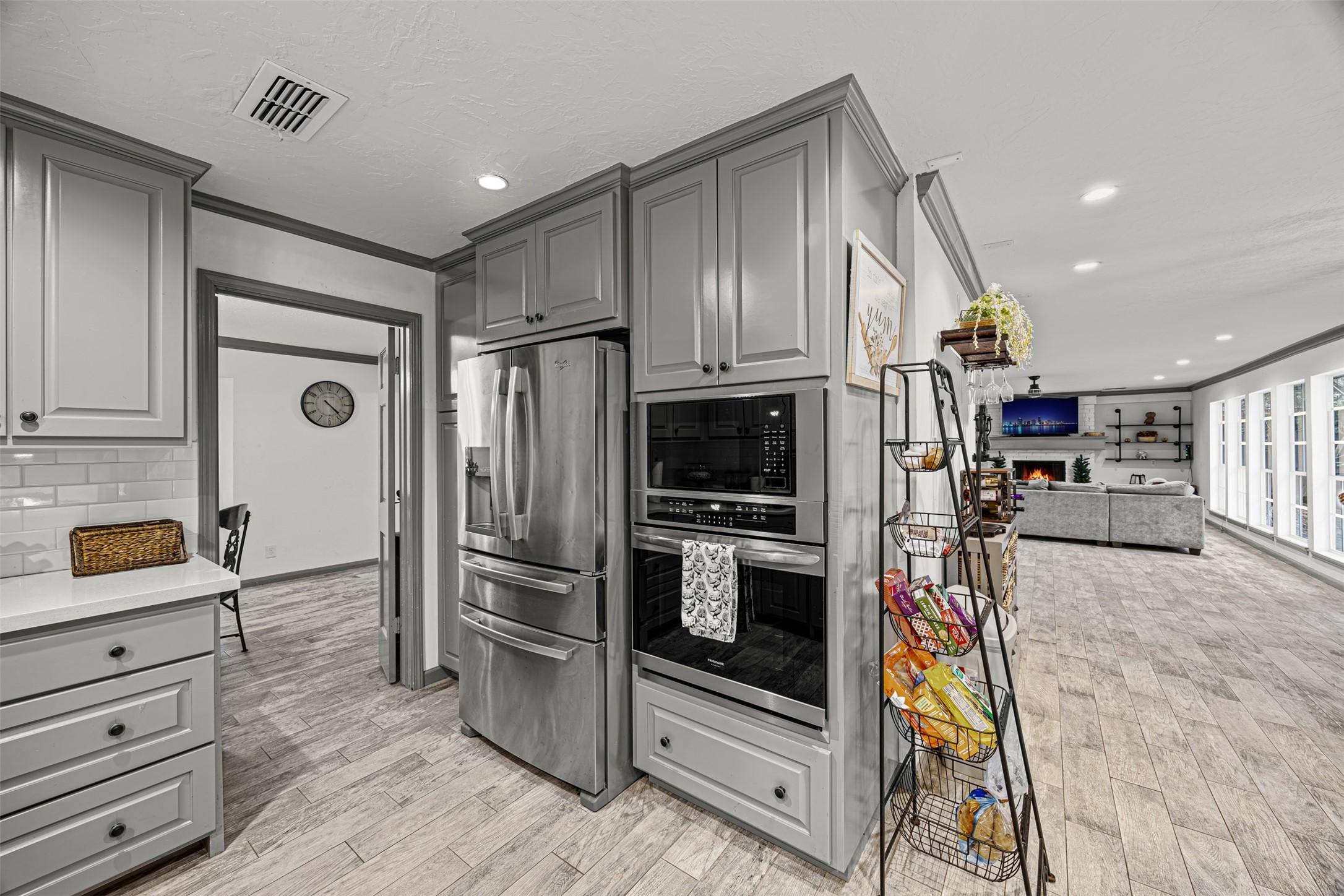 6511 Elmgrove Road Spring, TX 77389 - Photo 15 of 33 This photo showcases a modern open-concept kitchen and living area. The space flows seamlessly into a spacious living room with abundant natural light from large windows and a cozy fireplace, creating an inviting atmosphere.