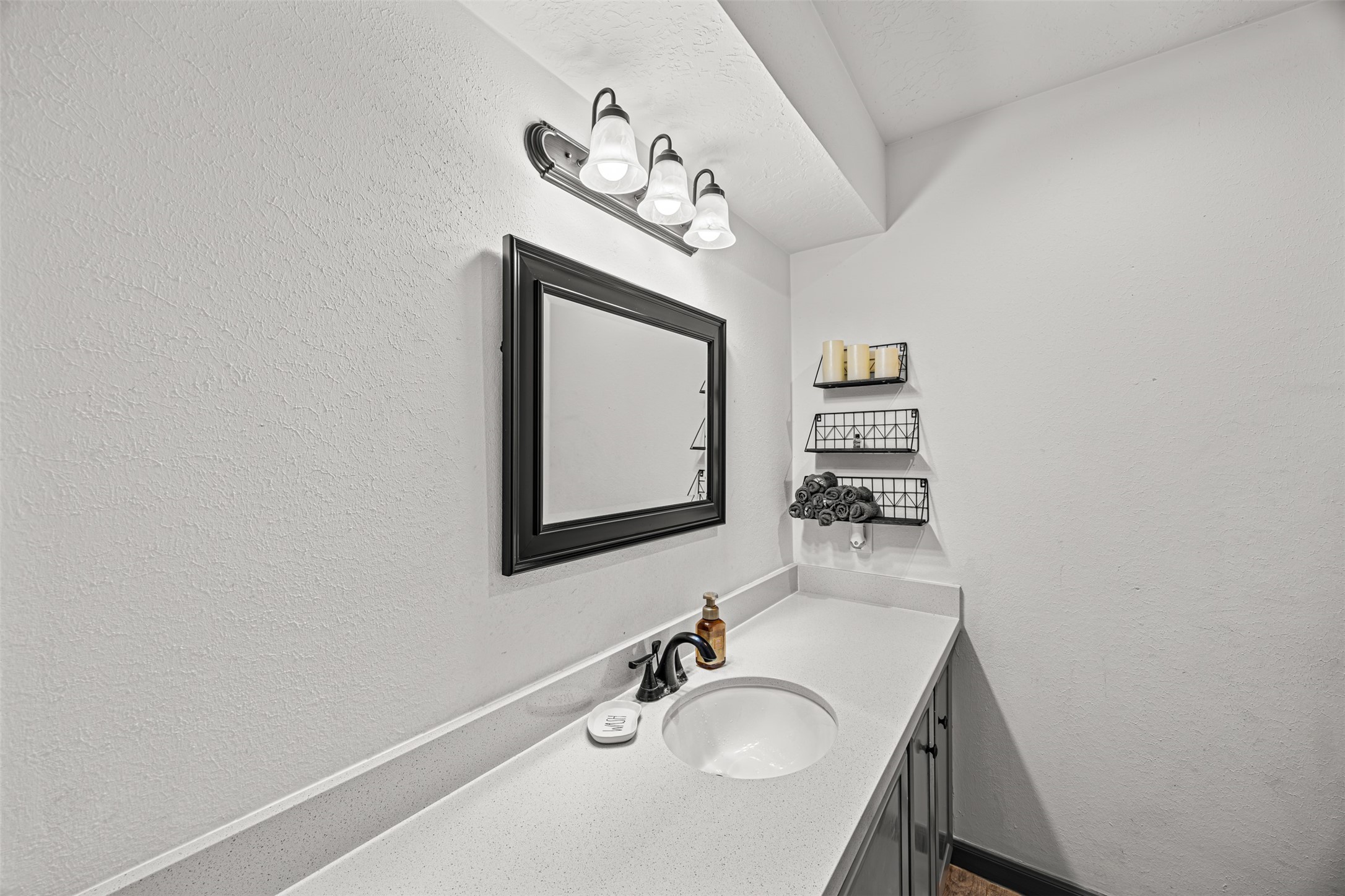 6511 Elmgrove Road Spring, TX 77389 - Photo 18 of 33 This bathroom features a sleek, modern design with a white countertop and sink, a stylish black framed mirror, and practical shelving for storage. Plenty of space for a vanity area.