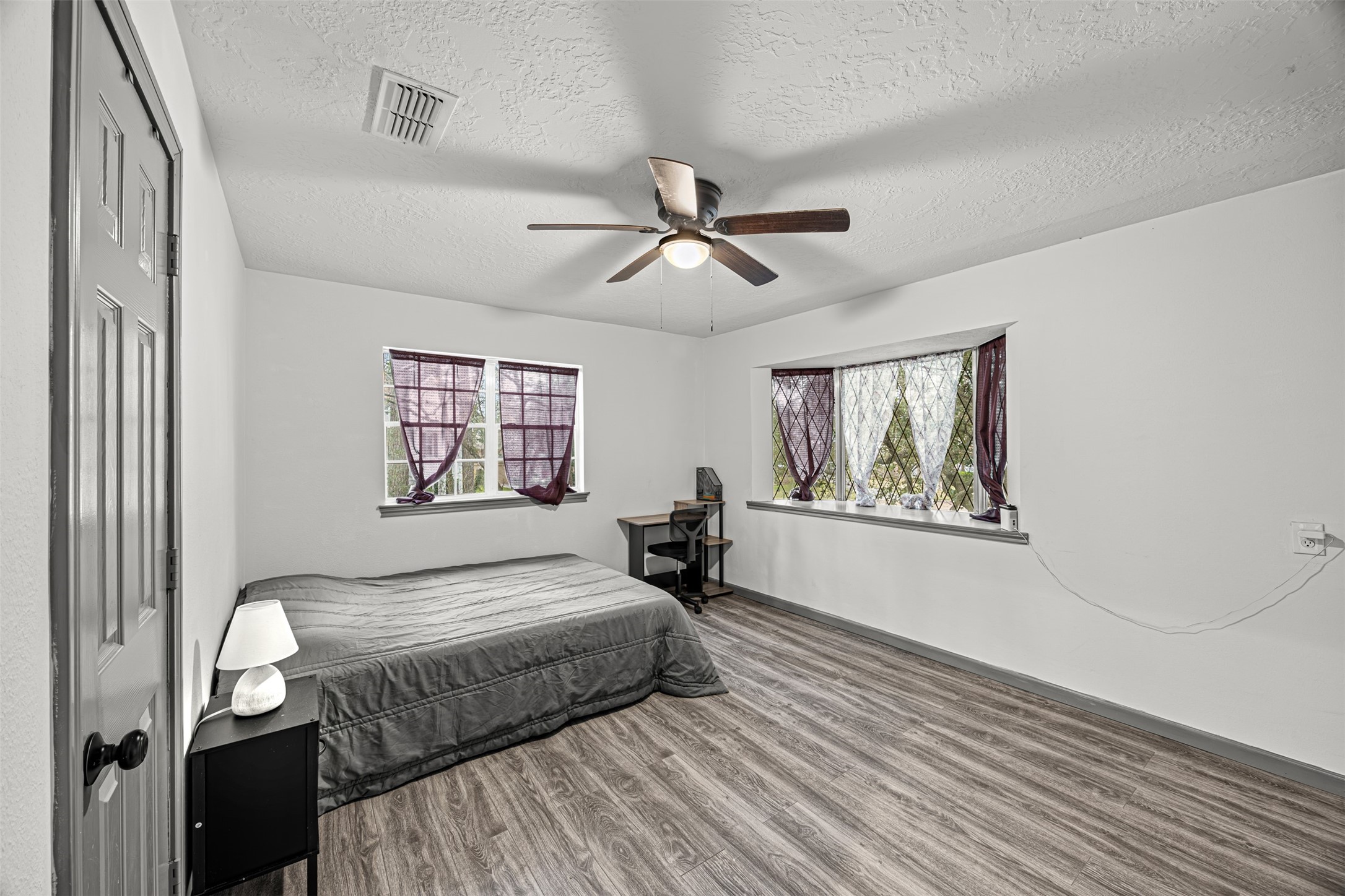 6511 Elmgrove Road Spring, TX 77389 - Photo 23 of 33 This room is bright and spacious with two windows allowing natural light. It features a ceiling fan, laminate flooring, and neutral walls.