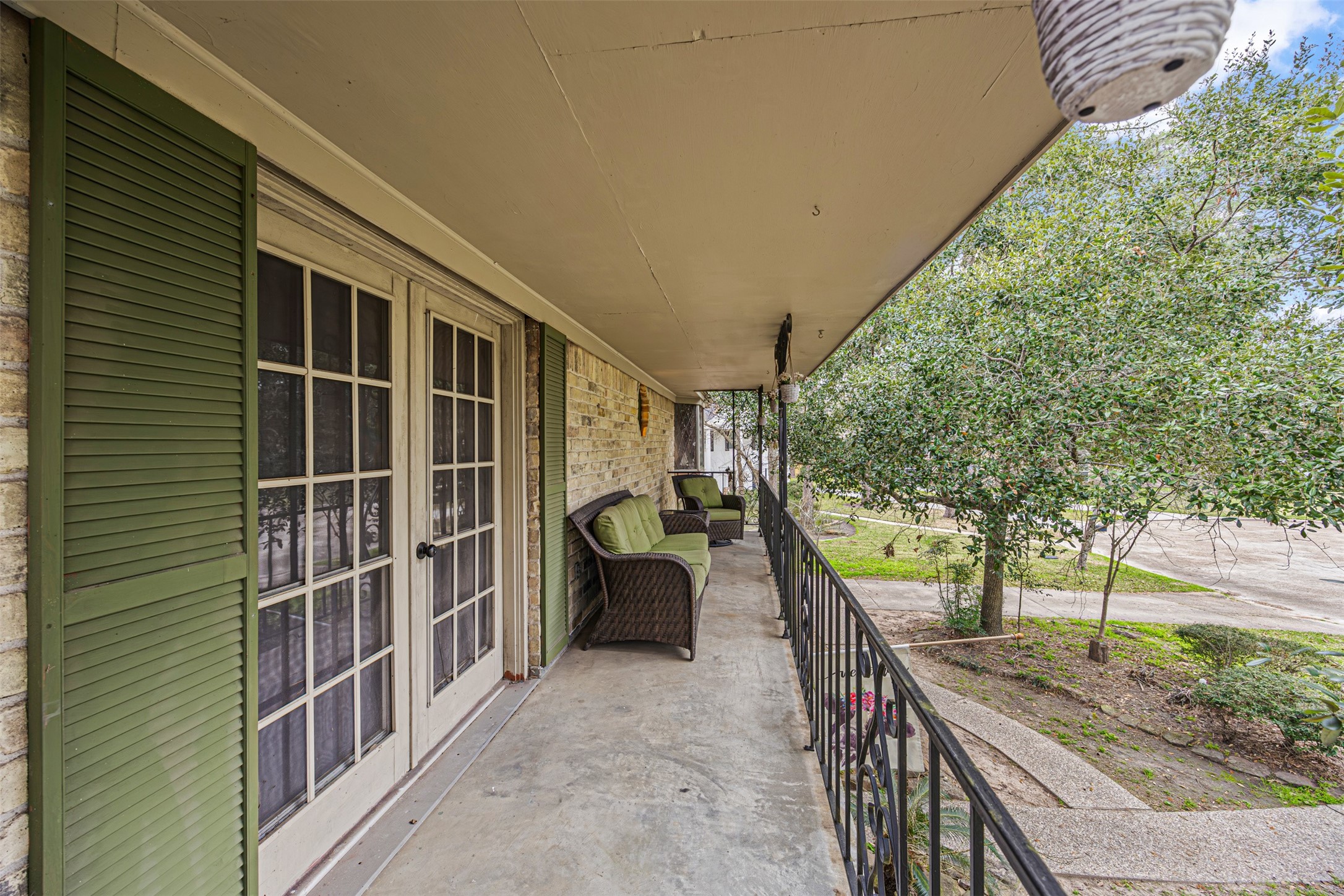 6511 Elmgrove Road Spring, TX 77389 - Photo 26 of 33 This photo shows French doors leading to a spacious front porch with green shutters, offering a cozy seating area perfect for relaxation. The balcony overlooks a well-maintained yard with mature trees, providing a pleasant and inviting outdoor space.