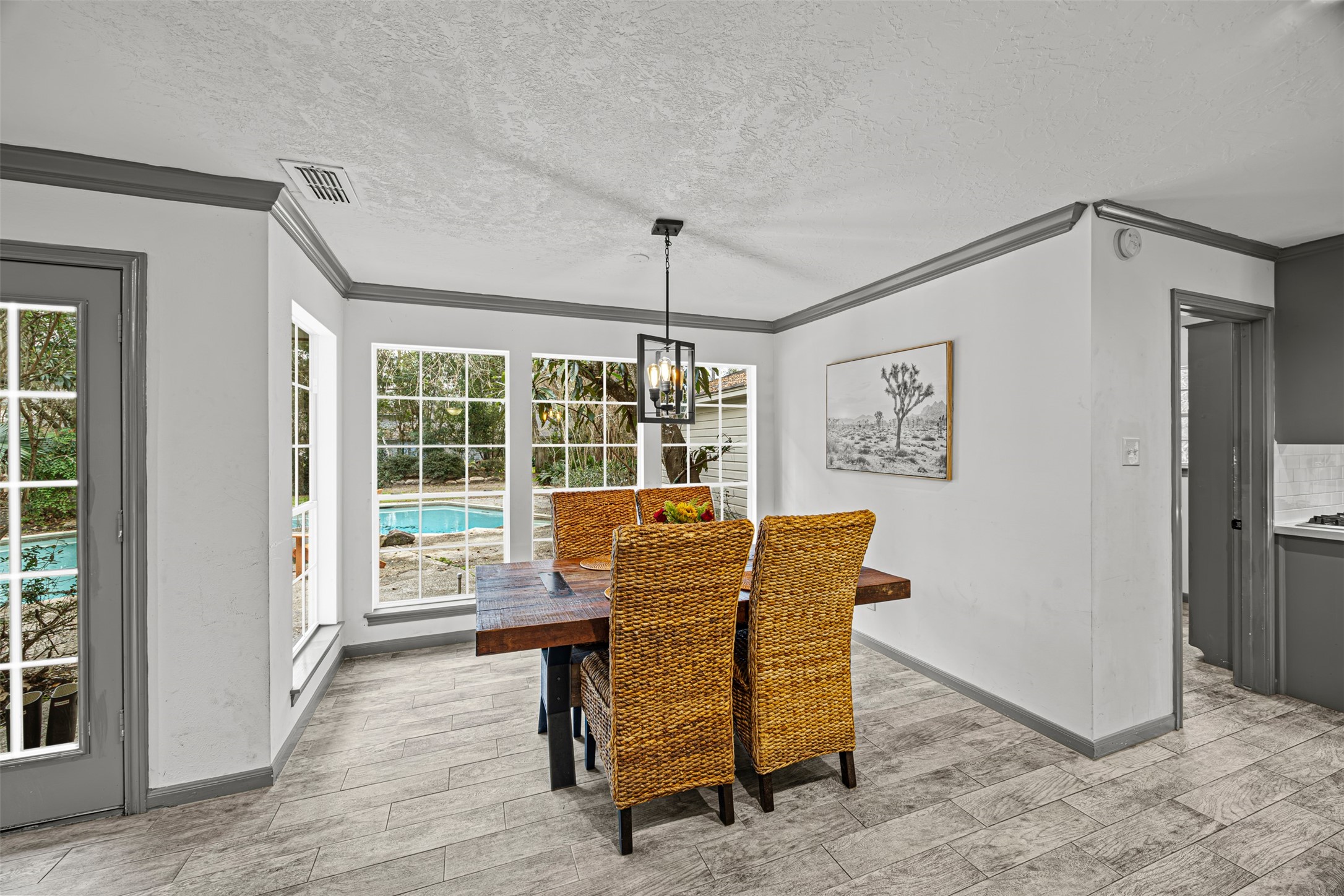 6511 Elmgrove Road Spring, TX 77389 - Photo 10 of 33 Bright dining area with large windows offering a view of the backyard pool. Features a wooden table with wicker chairs, a modern light fixture, and tiled flooring. Perfect for enjoying meals with a scenic outdoor backdrop.