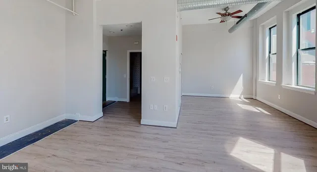 an empty room with wooden floor and windows