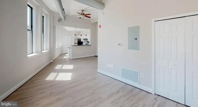 a view of empty room with wooden floor and fan
