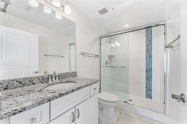 a bathroom with a granite countertop sink a toilet a mirror and bathtub